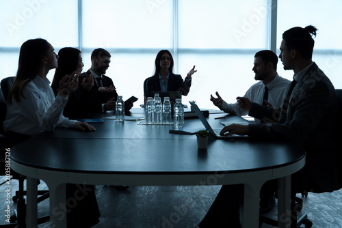 Silhouettes of business people working at table in office