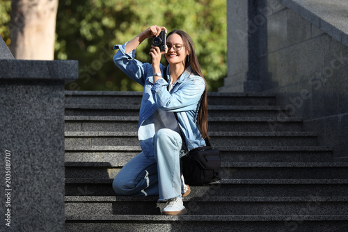 Foto Young woman photographer taking pictures with vintage camera on city stairs outd
