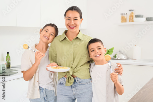 Young mother with her children and cottage cheese pancakes in kitchen