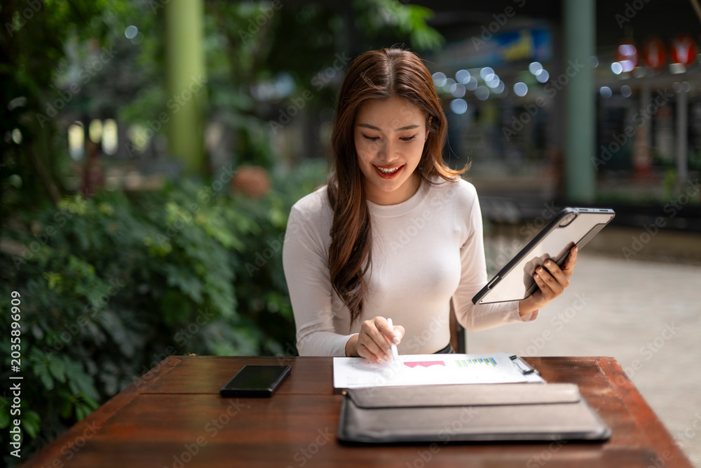 Obraz premium Asian businesswoman analyzing report data with digital pen