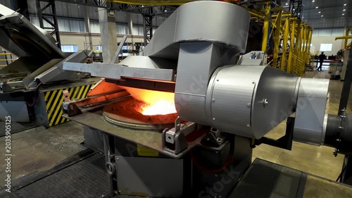 Cinematic industrial footage featuring molten metal pouring from a high-temperature furnace inside a modern manufacturing facility. Intense heat, glowing steel, sparks, heavy machinery, and industrial