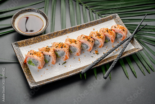 Photos Sushi rolls served on a plate with soy sauce and chopsticks on a dark table