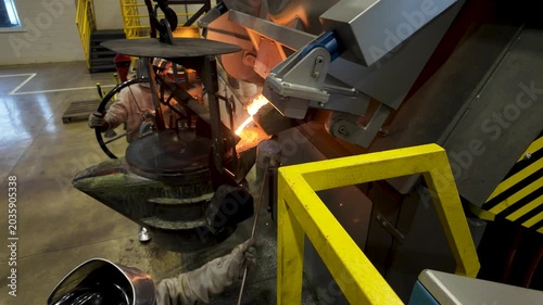 Cinematic industrial footage featuring molten metal pouring from a high-temperature furnace inside a modern manufacturing facility. Intense heat, glowing steel, sparks, heavy machinery, and industrial