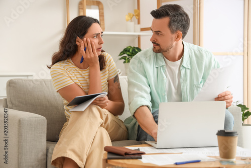 Schilderij op canvas Young couple using laptop to pay bills at home