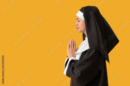 Young nun praying on yellow...