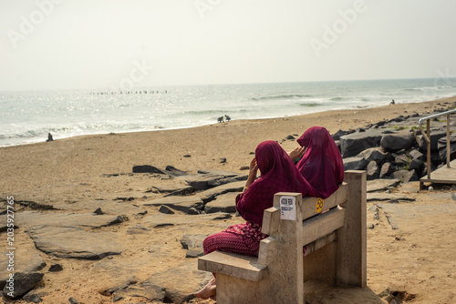 Foto Women wearing headscarves sitting by the sea