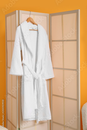 White bathrobe hanging on f...