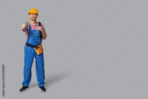 Quadro em tela Portrait of male electrician with crimper and wires on grey background