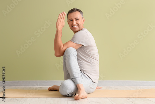 Mature man doing yoga on ma...