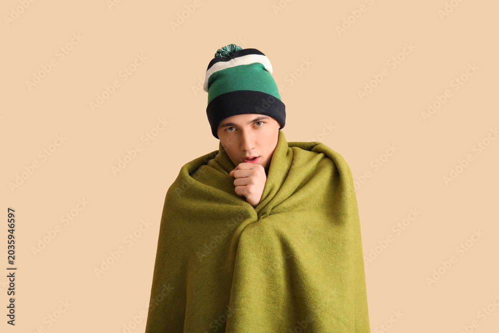 Fototapeta premium Ill young man with plaid on beige background