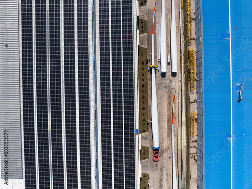 Aerial view of factory roof with solar panels and wind turbine blades