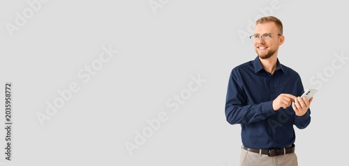 Handsome businessman working with mobile phone on light background with space...