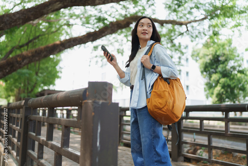Young woman navigating city park with smartphone