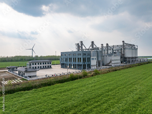 Fényképezés Modern industrial factory complex situated beside lush green fields under cloudy