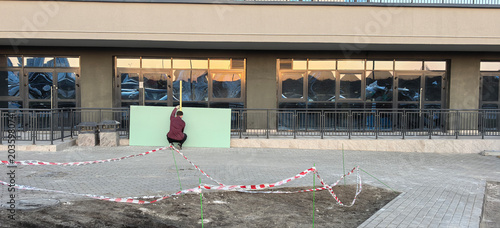 Schilderij op canvas Worker installs green panel on building wall in urban area during late afternoon