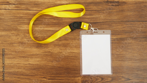 Yellow lanyard with blank badge isolated on wooden background	