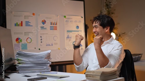 Successful businessman celebrating achievement working late in office