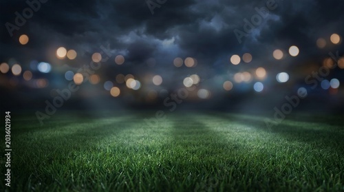 Dark empty soccer stadium grass pitch at night with blurred stadium lights