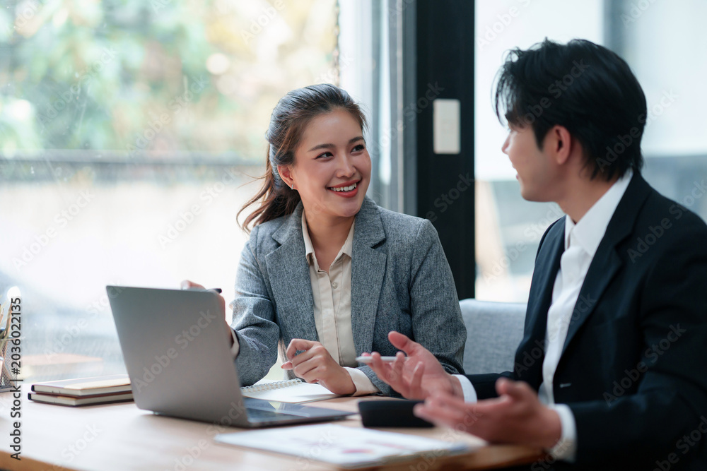 Obraz premium Two young asian business people actively discussing project ideas and strategies during a professional team meeting