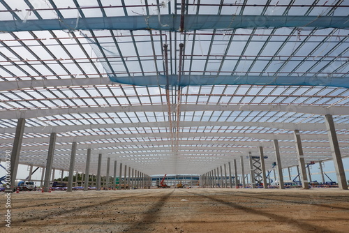 Quadro su tela Vast Industrial Construction Site: An expansive view of a large industrial building under construction, showcasing its massive steel framework and concrete pillars, symbolizing growth and development