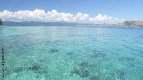 Side view from boat cruising across the blue waters near Komodo National Park, Hatamin island, Indonesia, with tropical islands, calm sea, and clear sunny sky