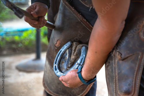 Schilderij op canvas Unknown farrier using hammer to fit and tighten horseshoe in stable