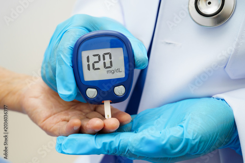 Bild auf Leinwand Asian doctor using digital glucose meter for check sample blood sugar level to treatment diabetes