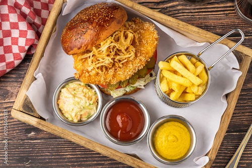 Crispy chicken burger with fries and sauces rustic fast food meal