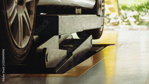 Close-up of a white car lifted on a hydraulic scissor hoist inside an auto repair shop, showcasing professional automotive maintenance, vehicle chassis inspection, and garage service.