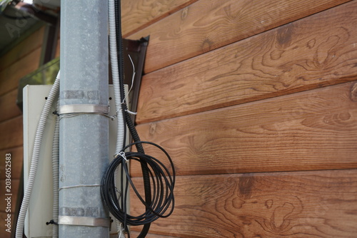 Detailed Examination of Utility Pole and Wooden Wall, Showcasing Electrical Wiring and Textured Natural Finish of Timber Construction