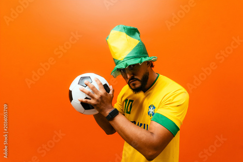 Brazilian soccer fan holding ball expressing expectation