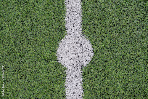 Top view of center mark on green artificial grass football field. Sports background with field texture and game concept.
