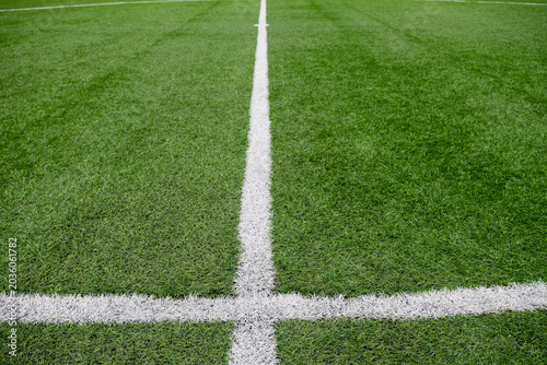 Close view of center circle and kickoff mark on green artificial turf football field. Sports background with white field lines and stadium surface details.