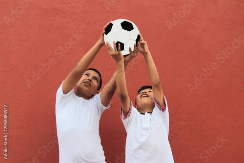 11-year-old Latino boys with dark skin show a soccer ball they play with and have fun practicing and doing sports