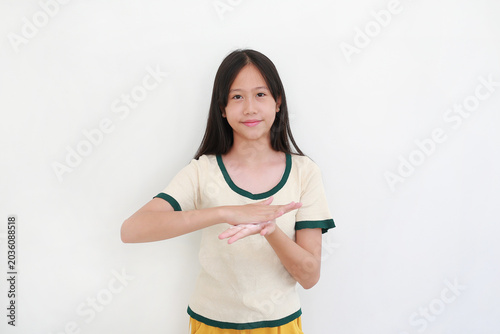 Smiling young Asian girl rubbing her hands together to apply moisturizing skin cream, isolated on white background.