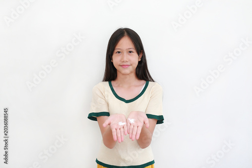 A smiling young Asian girl showing white moisturizing cream on both of her open palms, isolated on white background.