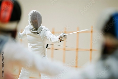 Fencer in action during competitive fencing match indoors