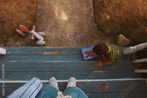 Bild auf Leinwand Parent watching child play with chalk on the front stoop