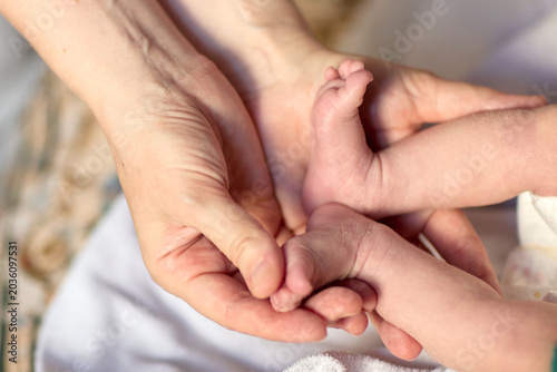 Close up of a newborn baby feet resting in caring adult hands during a gentle home care moment. Soft warm light, delicate skin details and tender touch create an emotional parenting and family scene.