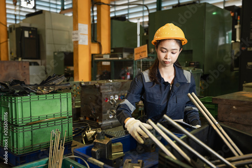Engineer woman or worker working and checking machine in warehouse for production supply