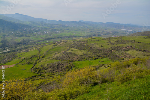 Beautiful landscape with mountains and blue sky. View on the mountains and green fields. Scenic nature view