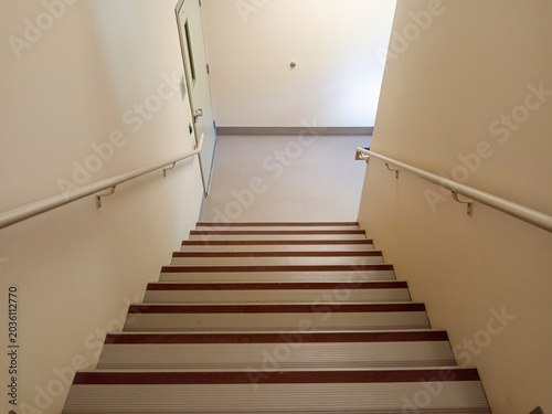 The stairwell shows safety handrails for an emergency exit in a nursing home building in Canada. The stairs lead to an exit door.