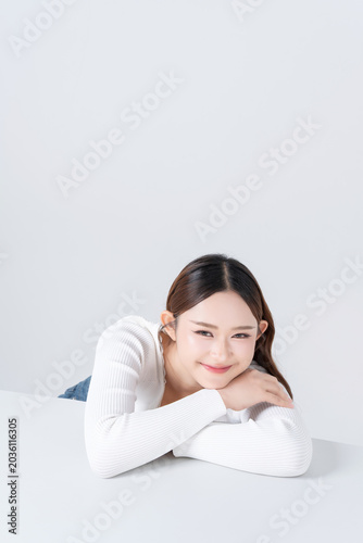 Beautiful young asian woman resting chin on hands with healthy skin on white background, for beauty, makeup and cosmetic concept.	