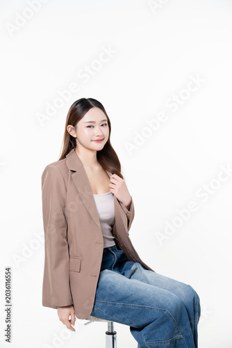 Beautiful Asian woman sitting on chair with glowing facial glass skin, healthy skin body and natural makeup, for advertisement skincare product and marketing beauty clinic on white background.