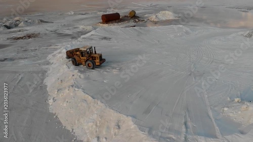 Yellow loader excavates salt pile on white flat under clear sky with other vehicles nearby creating active industrial harvesting scene ideal for mineral extraction and desert landscape stock video