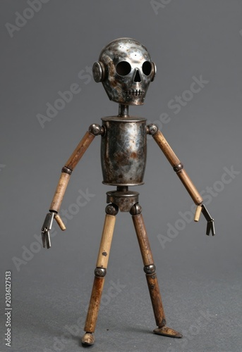 Rusty Metal Skeleton Robot Toy With Wooden Limbs Standing On Gray Surface