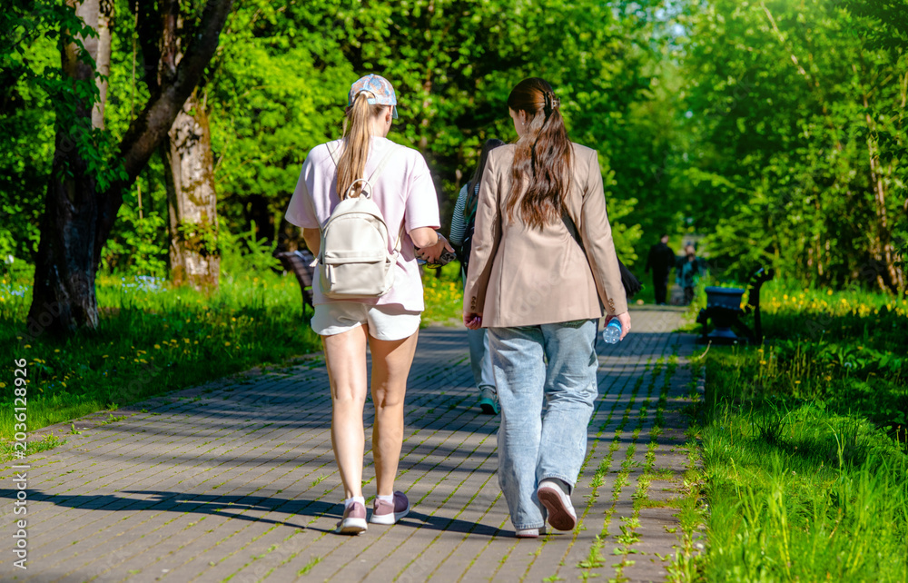 Obraz premium Two girlfriends walk along a path in the Park