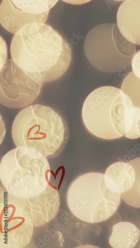Vertical video: Blue dot appearing warm bokeh shifting tinsel sparkling hearts spreading adding joy