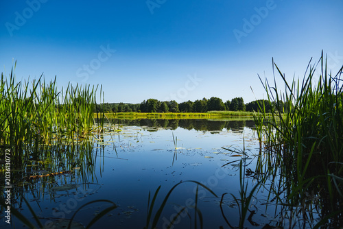Obraz na plátne a meandering lake with calm, mirror-like waters in which the landscape is reflec