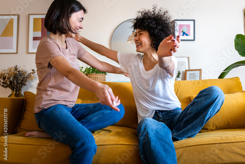 Foto Happy friends greeting hugging on a yellow sofa